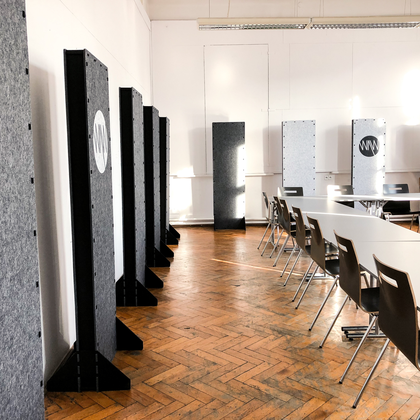 Customized sound absorbing acoustic screens with a custom logo standing against the wall in the lecture room with reverberation issues.